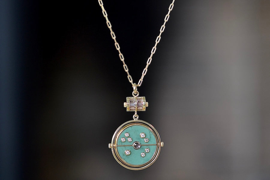 Grandfather Compass Pendant in Green Turquoise and Tanzanite by Retrouvai is a pendant necklace with stone inlay that is accented with a center gem stone in the front and back, and nine (9) round white diamonds. The compass hangs from a barrel and on a paperclip link chain in 14k yellow gold of 26" .