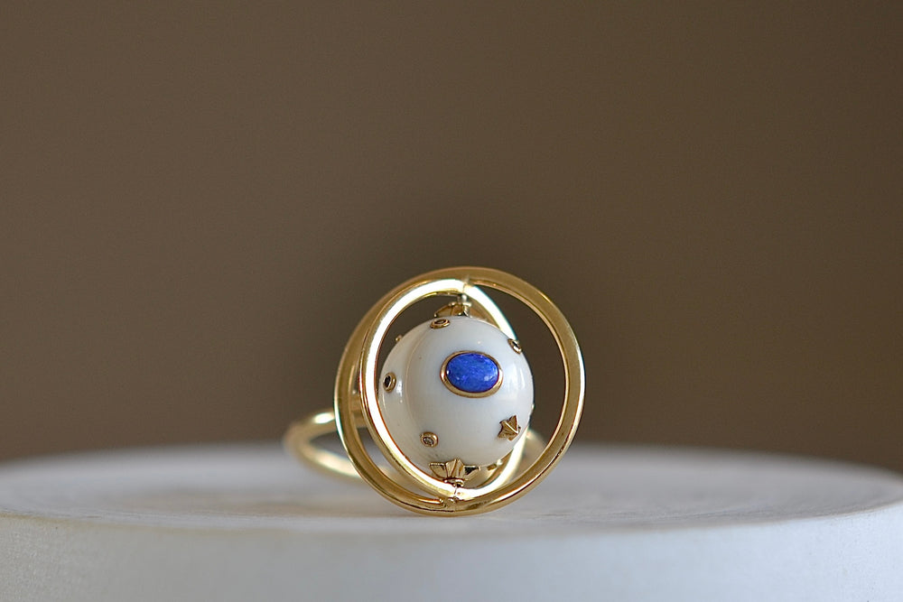 Galaxy Spinning ring by Bibi Van Der Velden is a sphere of white mammoth tusk with diamonds, opals and blue sapphires. 