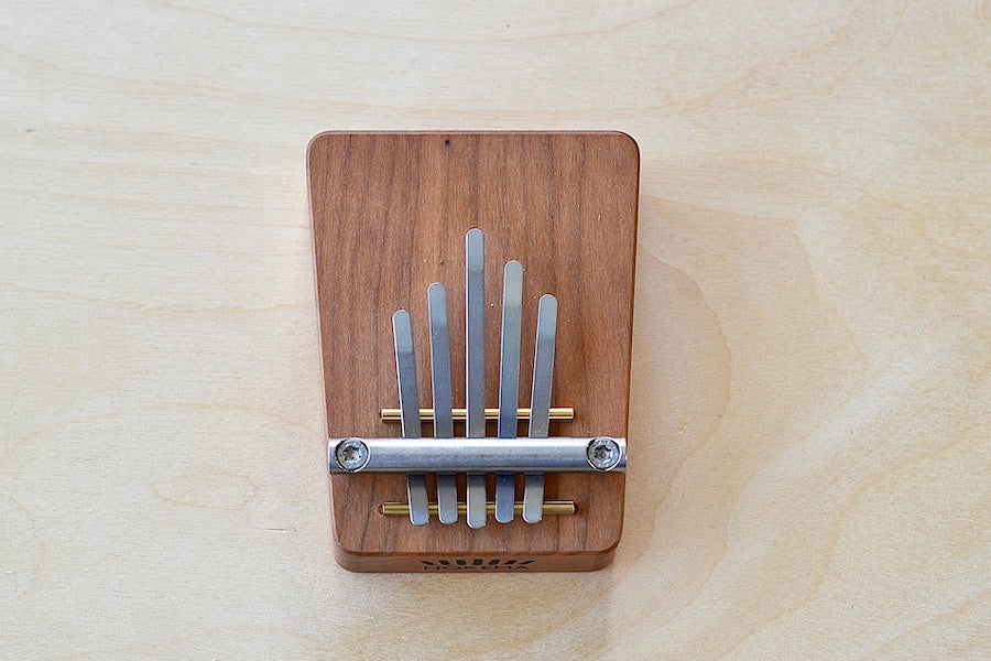 Birds eye view of small kalimba with five (5) metal tines.