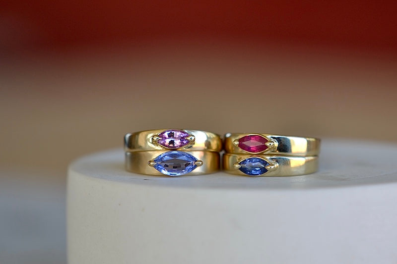 Stoned Slim Cigar Band in purple to lilac Sapphire size 6.5 by Elizabeth street is a marquise cut sapphire in a two prong eagle claw bezel setting on a 14k yellow gold band.