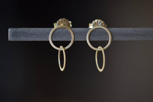 Double Circle Stud Earrings by Carla Caruso are Two thin and flat interlocked circles in 14k yellow gold and satin finish with post closure.