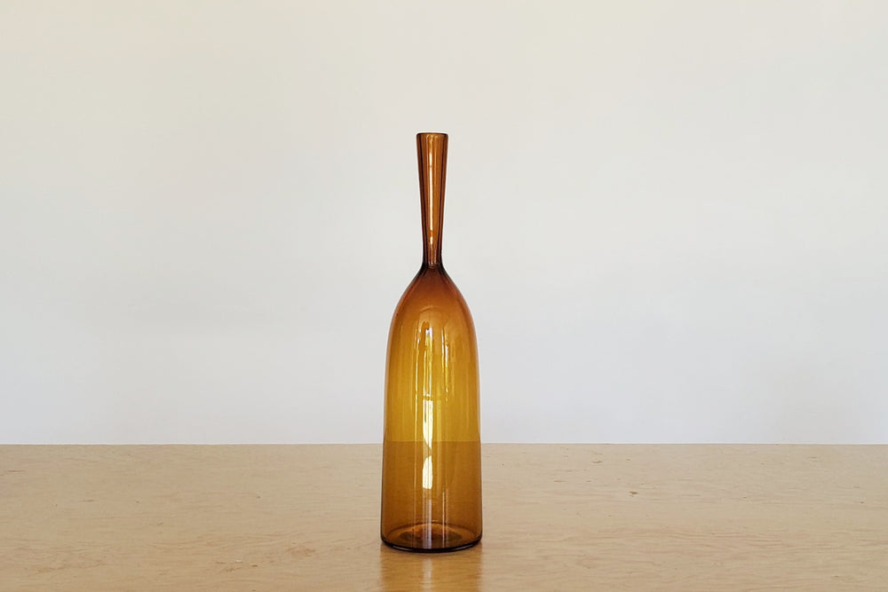 Angelic Bottles by Joe Cariati are mouth blown  Freeblown by glass master Joe Cariati in his Southern California studio, these bottle-form vases evoke the more mass produced mid-century ones that inspired them, small amber orange.