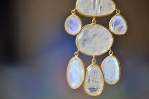 The Baroque Pendant in Moonstone and 18K by Pippa Small is Eight stones that are organically shaped, lightly faceted, translucent milky white and iridescent are arranged in a baroque pattern, all are bezel set in 18k yellow gold and attached with hooks to hang on a 24" golden waxed cotton cord to form this statement necklace.  