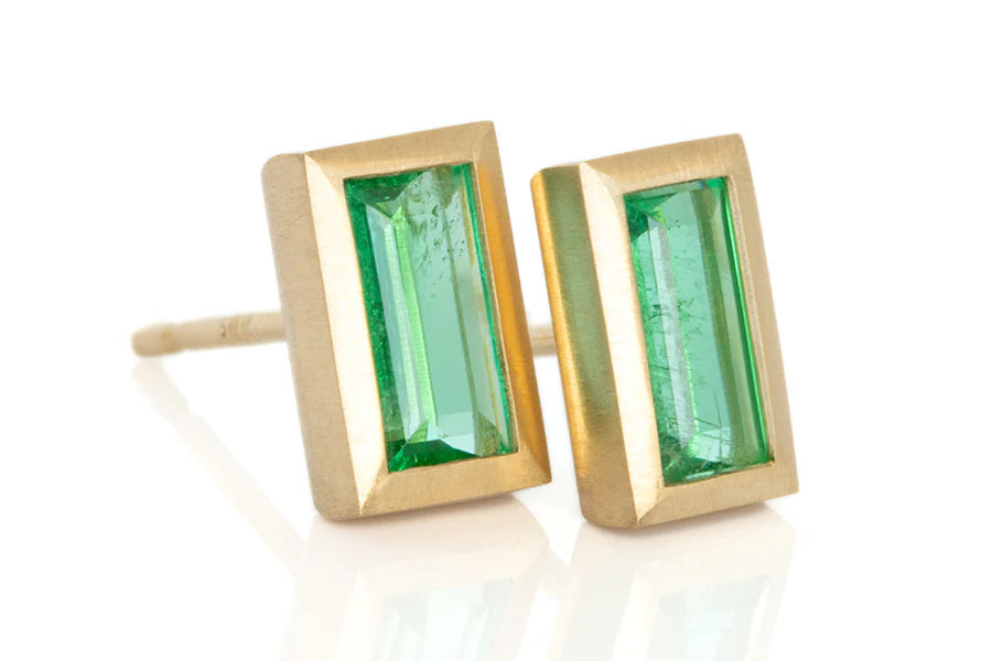 Studio shot of elongated emerald earrings.