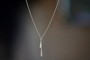 Double Fringe Necklace designed by Carla Caruso is  one long and one short elongated teardrop fringe have been hand shaped, hammered and hung from a ring that is connected to a chain in 14k yellow gold with satin finish.