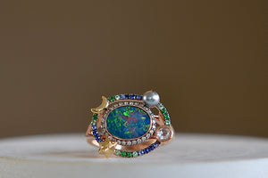 
            
                Load image into Gallery viewer, Small Galaxy Opal Ring by Bibi Van Der Velden is a rose gold ring with an opal, surrounded by a ring of brown pave diamonds, another ring of blue sapphires and green pave tsavorites, a gray keshi pearl, a white rose cut diamond, a star and moon in yellow gold. 
            
        