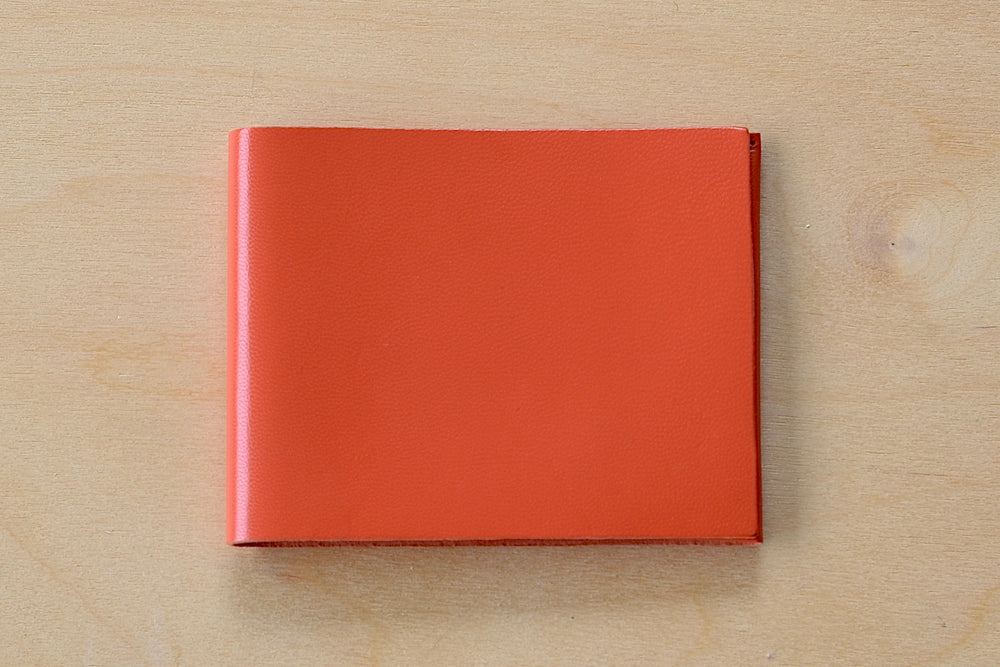 Simple flap wallet by Alice Park in orange is perfect fit for dollar bills with space for cards.