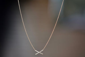 Mini X Necklace by Carla Caruso is a small inline X on a chain in 14k yellow gold with satin finish.