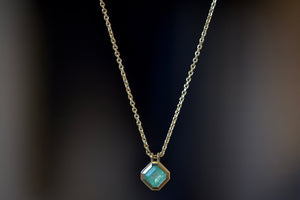 
            
                Load image into Gallery viewer, The Duo Bale Offset Emerald Necklace by Elizabeth Street is a bezel set, translucent and rectangular shaped Columbian emerald hanging on an axis with twin bales and on a 14k yellow gold chain. 
            
        
