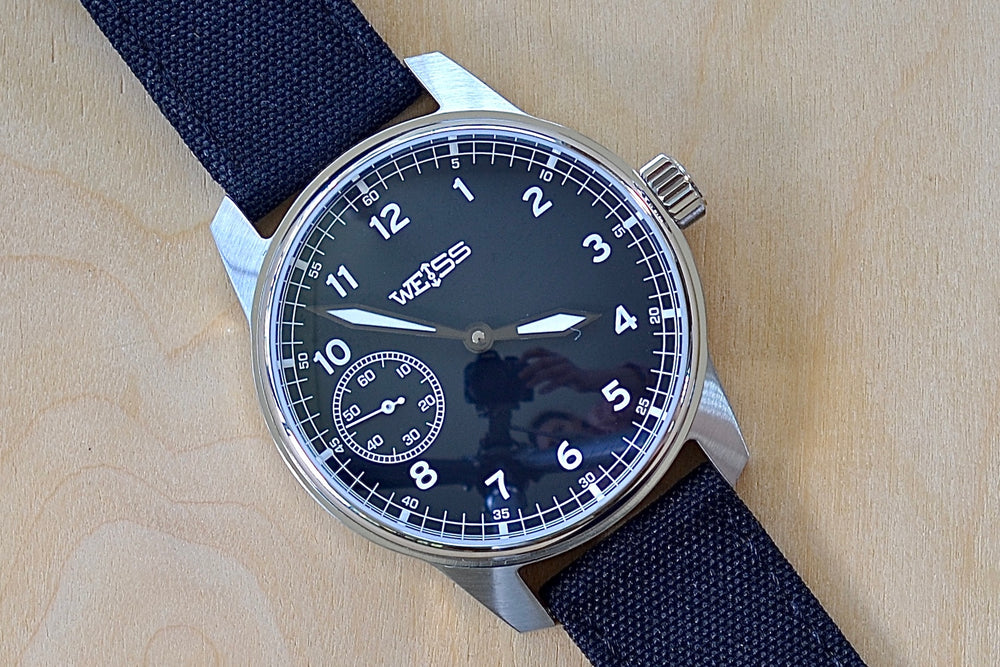 
            
                Load image into Gallery viewer, Weiss Watch 42mm Standard Field Watch with Black Dial, shown with black canvas strap is manually wound, made with American parts, featuring Super Luminova hands and markers.
            
        