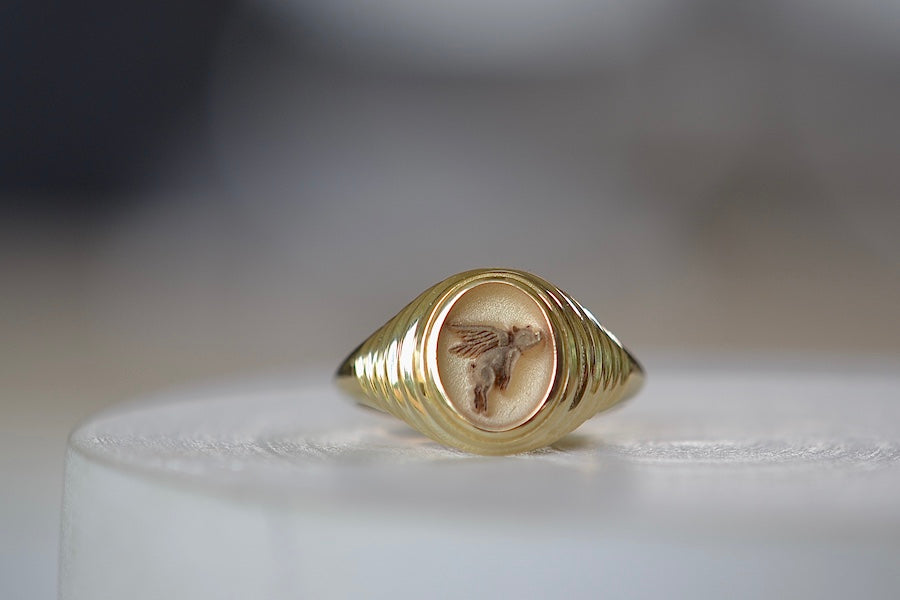 A Retrouvai Baby Fantasy Signet in Flying Pig is a 14k polished and tiered yellow gold pinky ring with an engraving that reads 'anything is possible'. Unisex jewelry.