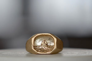 Sailboat Signet Ring by Fraser Hamilton is a square and solid signet with inset relief of a sailboat and sediment texture on the band in 9k yellow gold.