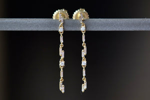 
            
                Load image into Gallery viewer, Linear Drop Earrings Designed by Suzanne Kalan are a sculptural combination of bezel set white baguette and round diamonds hang on a gold bar to form these dangle earrings with stud post closure. 
            
        