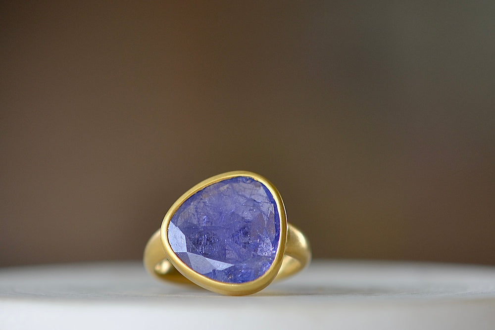 The Tanzanite Greek Ring by Pippa Small Jewellery is an organically shaped, and hand cut, bright purple, faceted and translucent tanzanite stone set in 18k yellow gold. Size 6 in stock.