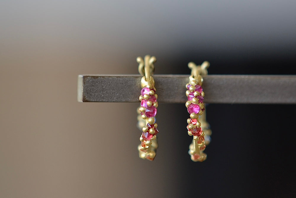 Polaris Vine Earrings in Rainbow Sapphires designed by Polly Wales are a small round hoop in 18k gold has an encrusted vine with inverted rainbow sapphires in yellow, pink, orange, green, blue and purple along with matte gold dots.