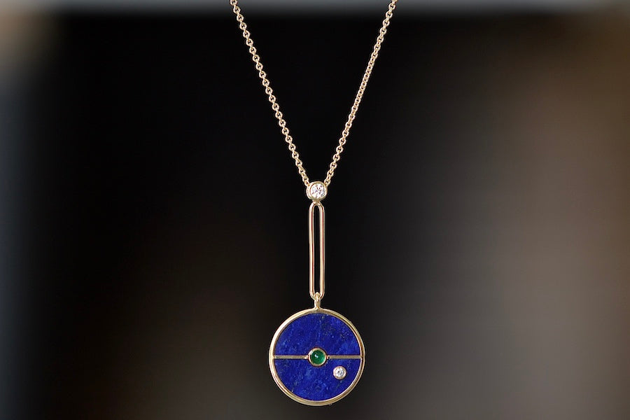  The signature Compass Pendant with Lapis and Emerald by Retrouvai is a pendant necklace with stone inlay that is accented with a center gem stone and a white diamond. The compass hangs from an elongated paperclip link accented with a second white diamond on 24" 14k yellow gold chain.