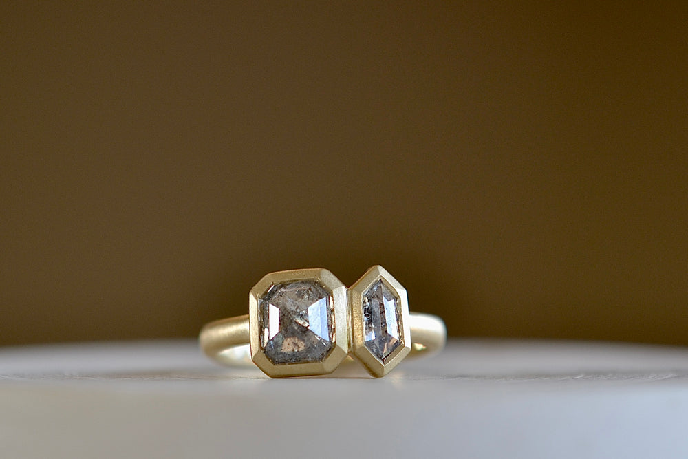 Duo Salt and Pepper Diamond Band by Elizabeth Street Jewelry is Two bezel set and faceted mix shape salt and pepper diamonds next to each other on a matte 14k yellow gold band One is hexagon cut and the other is a rose cut square 'Toi et Moi'. 