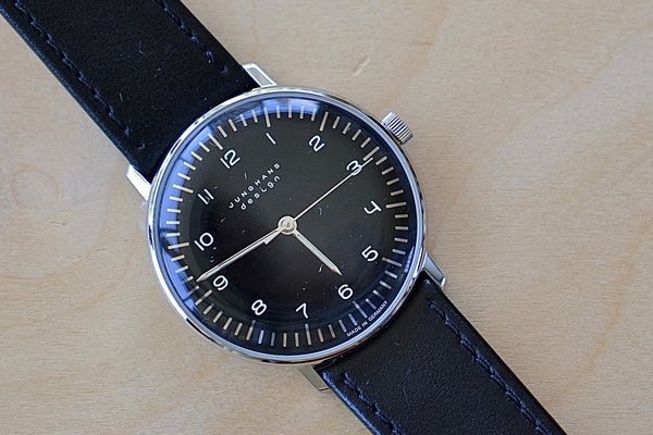 Max Bill 34mm Hand wound Watch Black Dial with Numbers designed for Junghans in 1961 and virtually unchanged. 34mm hand wound watch with black face and numbers with hand winding movement J805.1 (ETA 2801-2) and a sapphire crystal,  42 Hour Power Reserve in 316L stainless steel case available at OK..