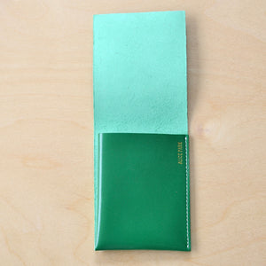 Kelly green flap wallet by Alice Park  with white stitching.