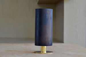 The Aubock Vase on Pedestal in Medium 7247-4 is a thin rimmed patina brass tube vase with polished base in medium designed by Carl Auböck.