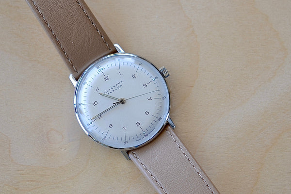 Max Bill 34mm Hand-wound Watch in White Dial with Numbers designed for Junghans in 1961remains virtually unchanged. 34mm hand wound watch with black face and numbers with hand winding movement J805.1 (ETA 2801-2) and a sapphire crystal,  42 Hour Power Reserve in 316L stainless steel case available at OK.