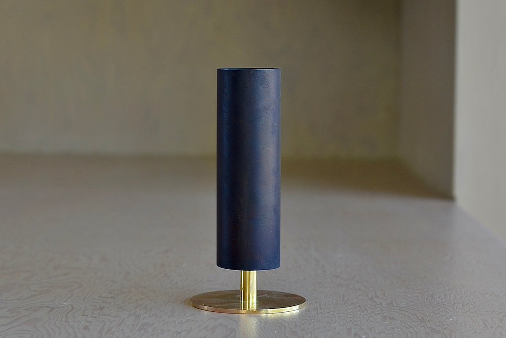 The Aubock Vase on Pedestal in small 7247-2 is a tall and thin rimmed patina brass tube vase with polished base in small. designed by Carl Auböck.
