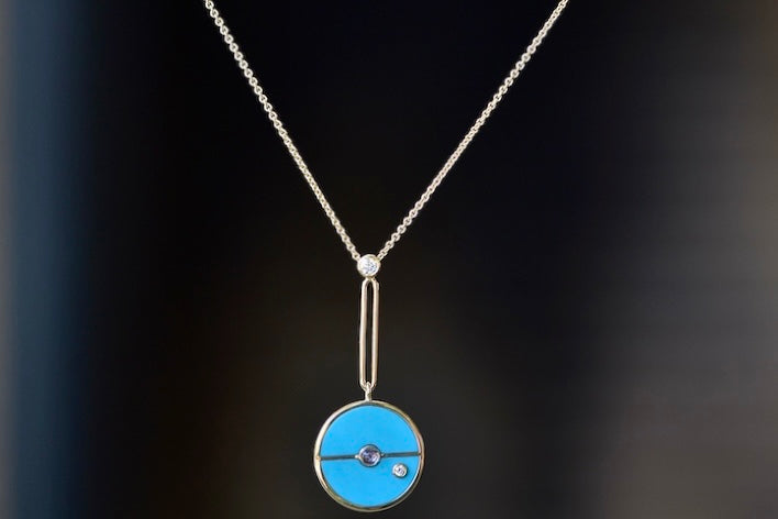 
            
                Load image into Gallery viewer,  The signature Compass Pendant with Sleeping Beauty Turquoise and Tanzanite by Retrouvai is a pendant necklace with stone inlay that is accented with a center gem stone and a white diamond. The compass hangs from an elongated paperclip link accented with a second white diamond on 24&amp;quot; 14k yellow gold chain.
            
        