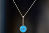  The signature Compass Pendant with Sleeping Beauty Turquoise and Tanzanite by Retrouvai is a pendant necklace with stone inlay that is accented with a center gem stone and a white diamond. The compass hangs from an elongated paperclip link accented with a second white diamond on 24" 14k yellow gold chain.