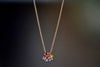 Daisy necklace by Polly Wales with pink cabochon center and rainbow  nverted and encrusted brilliant sapphires in hot pink, pink, lilac, blue, orange, green, and yellow. 