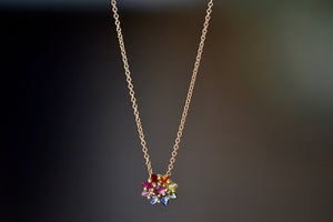 Daisy necklace by Polly Wales with pink cabochon center and rainbow  nverted and encrusted brilliant sapphires in hot pink, pink, lilac, blue, orange, green, and yellow. 