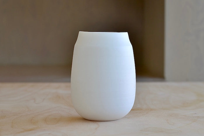 Lilith Rockett Vase with Neck "D" is Reminiscent of an eggshell, this vase is wheel thrown porcelain with gloss glaze on the interior and an unglazed exterior. It has been sanded smooth and it is very stable despite its rounded bottom. 