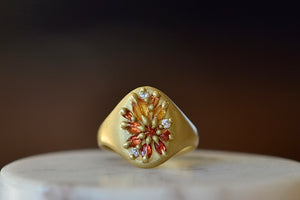 Encrusted Lotus signet ring by Polly wales in orange sapphires with white diamonds on 18k polished yellow gold band.