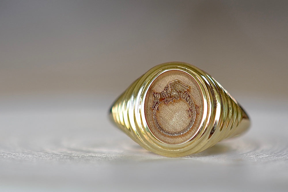 The Ouroboros Baby Fantasy Signet by Retrouvai is a 14k yellow gold ring with a picture of a snake on a tiered edging that gives this classic signet a modern take. The engraving on the back reads nothing is static.