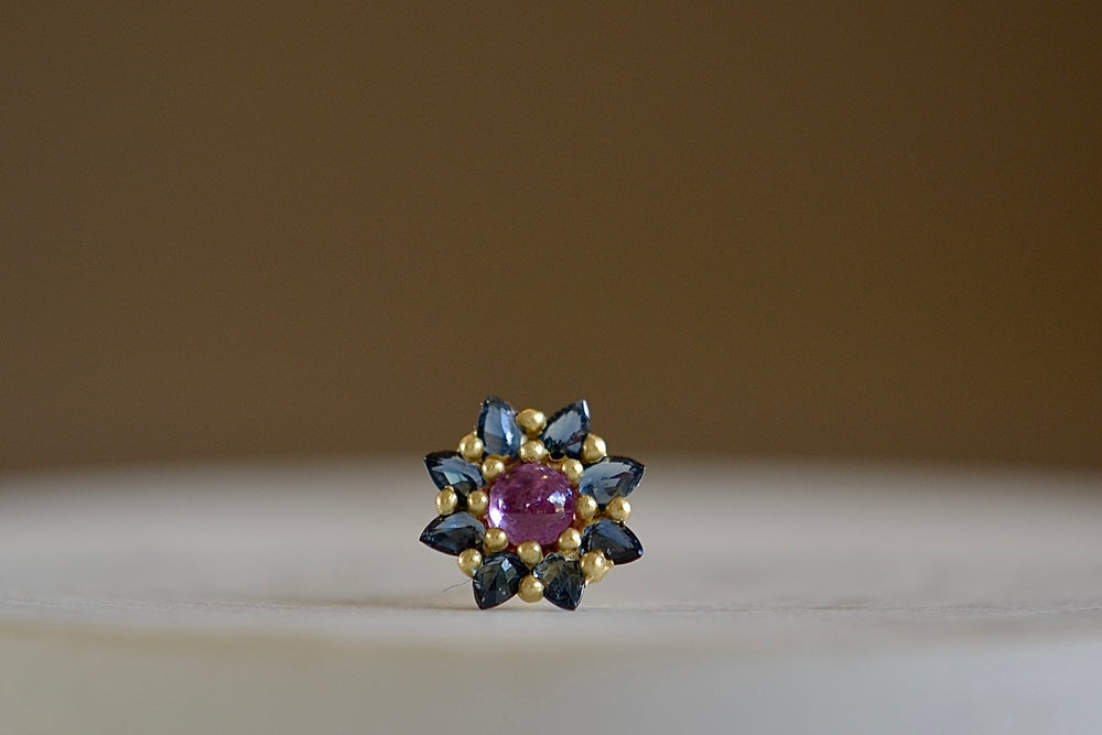 The Daisy stud by Polly Wales is a floral cluster made out of a half sphere in gold with a cabochon and encrusted inverted brilliant sapphires. We have one in pink and teal.