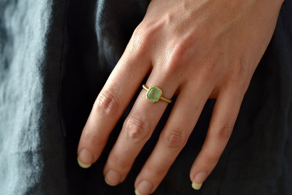 Wearing the simple Emerald Rectangular ring by Elizabeth Street made with a pale Columbian emerald.
