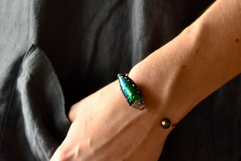 
            
                Load image into Gallery viewer, Wearing the Scarab Pearl bangle by Bibi Van Der Velden is a bracelet bangle in 18k rose gold and sterling with  brown diamonds, a  scarab wing in amethyst  with pink sapphire, tsavorite and a Tahitian pearl.
            
        