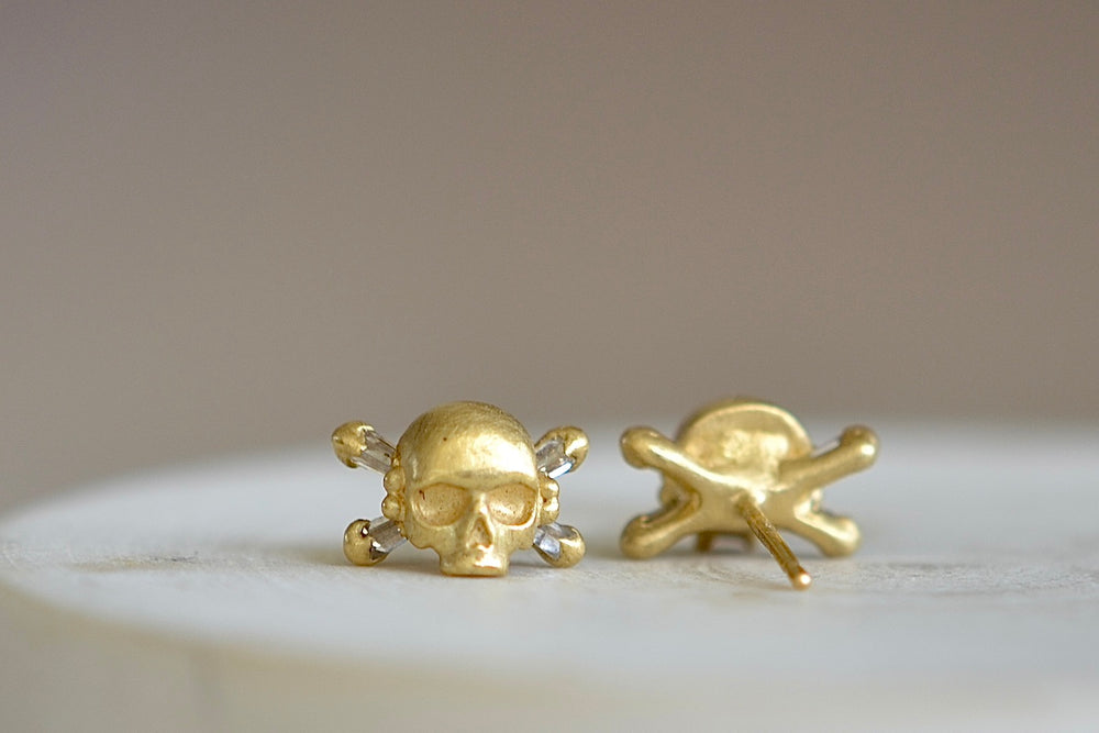 Back and front of Polly Wales skull and bone earrings in 18k gold.