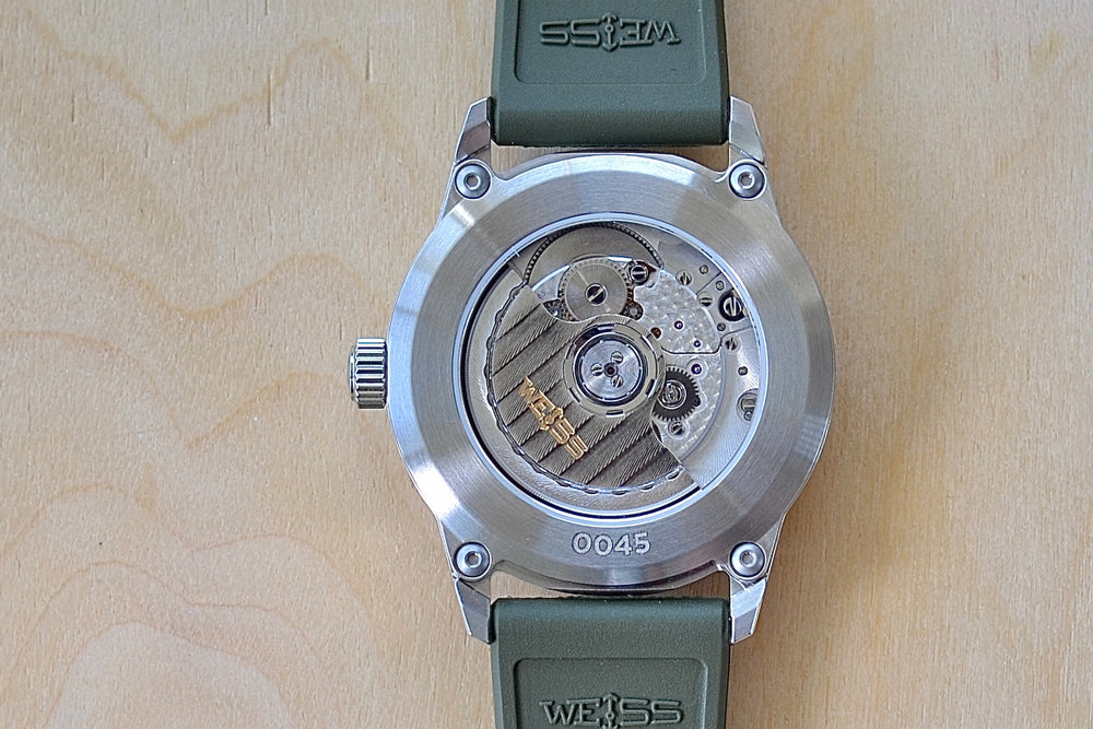 
            
                Load image into Gallery viewer, Back of Weiss Watch 38mm Automatic Field Watch with Black Dial and date, shown with olive rubber strap , made with American parts. 
            
        