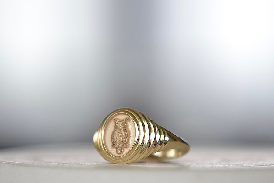 Angled view of the A Retrouvai Baby Fantasy Signet in Flying Owl is a 14k polished and tiered yellow gold pinky ring in size 6.5. Unisex jewelry.