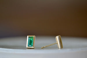 Side view of Elongated Emerald stud earrings with Zambian stone and bezel set in satin finish 14k yellow gold with post closure.