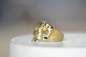 Side view of Stoned Mini Snaggle Tooth Skull ring by Polly Wales with green sapphires and a baguette diamond snaggle tooth.