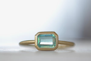 Full frontal on the Simple Green Emerald ring by Katie Finn and Elizabeth Street Jewelry is a bezel set solitaire in green Emerald on a 14k satin yellow gold band.