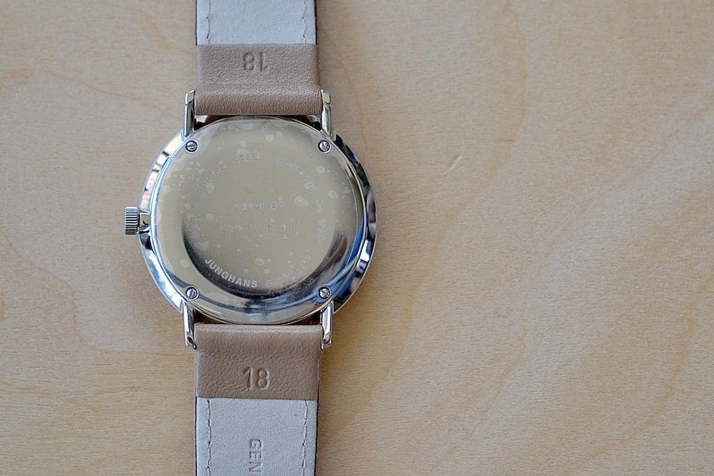 Back of Max Bill 34mm Hand-wound Watch in White Dial with Numbers designed for Junghans in 1961remains virtually unchanged. 34mm hand wound watch with black face and numbers with hand winding movement J805.1 (ETA 2801-2) and a sapphire crystal,  42 Hour Power Reserve in 316L stainless steel case available at OK.