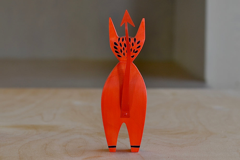 View from the back of The Wooden Little Devil is a bright red decorative figurine that is part of the Alexander Girard doll collection.