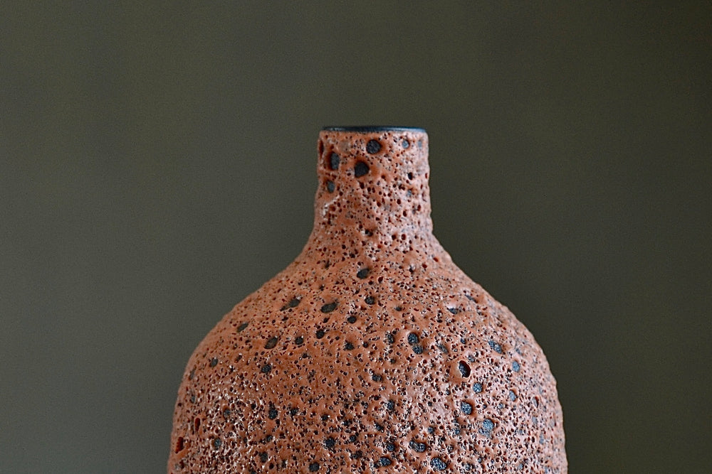 
            
                Load image into Gallery viewer, Detail of Heather Rosenman orange ceramic bottle vase in volcanic glaze.
            
        