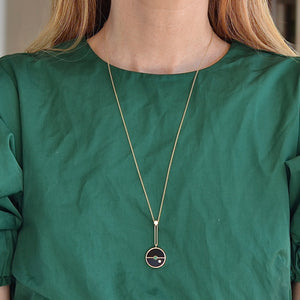 
            
                Load image into Gallery viewer, Wearing the signature Compass Pendant with Black Onyx and emerald by Retrouvai is a pendant necklace with stone inlay that is accented with a center gem stone and a white diamond.
            
        