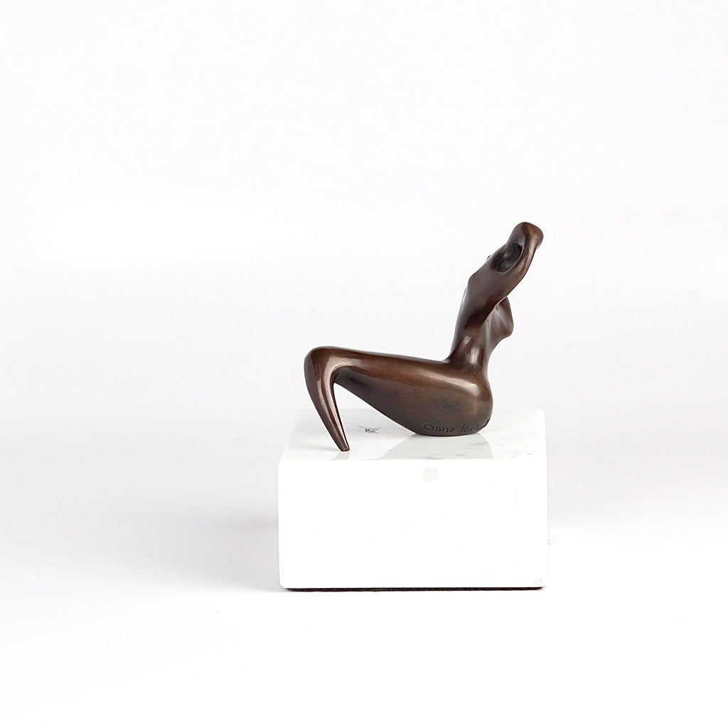 Anne Ricketts Repose Sculpture of modern woman in brass on white background.