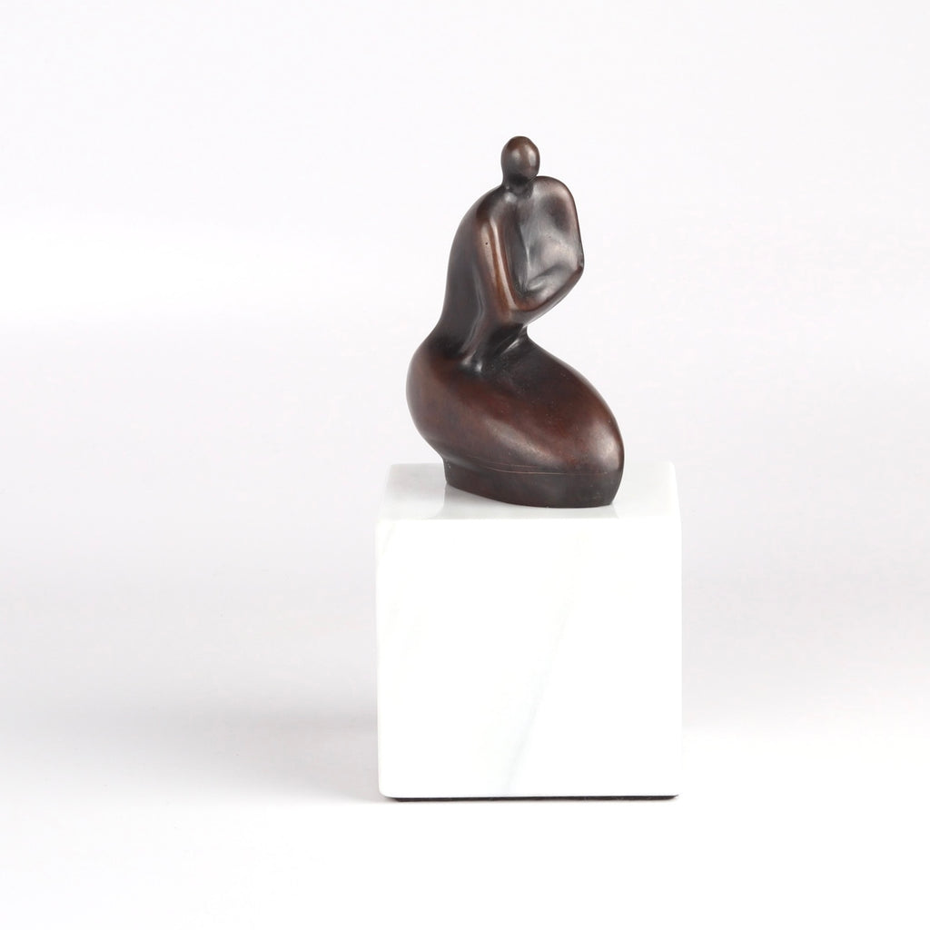 Anne Ricketts Berecuse Sculpture of modern woman in brass on white background.