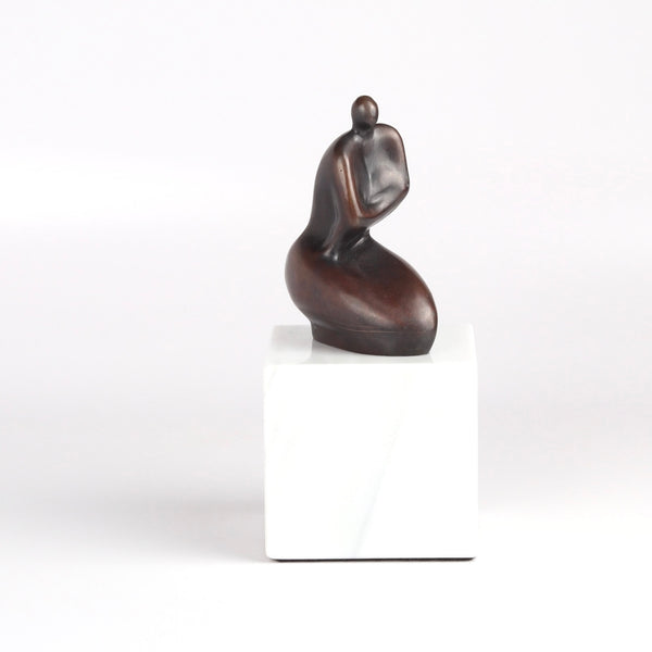 Anne Ricketts Berecuse Sculpture of modern woman in brass on white background.