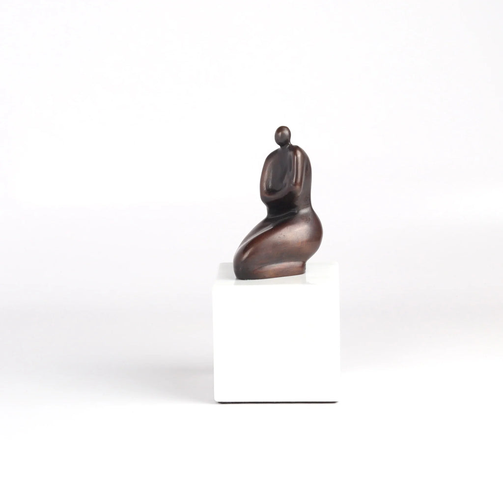 Anne Ricketts Berecuse Sculpture of modern woman in brass on white background.